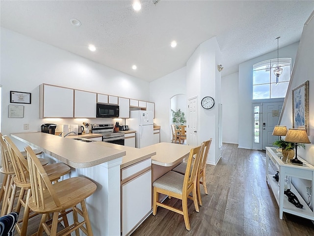 344 Bloomingdale Dr, Davenport, FL 33897 - kitchen featuring freestanding refrigerator, electric stove, black microwave, light countertops, and a kitchen breakfast bar