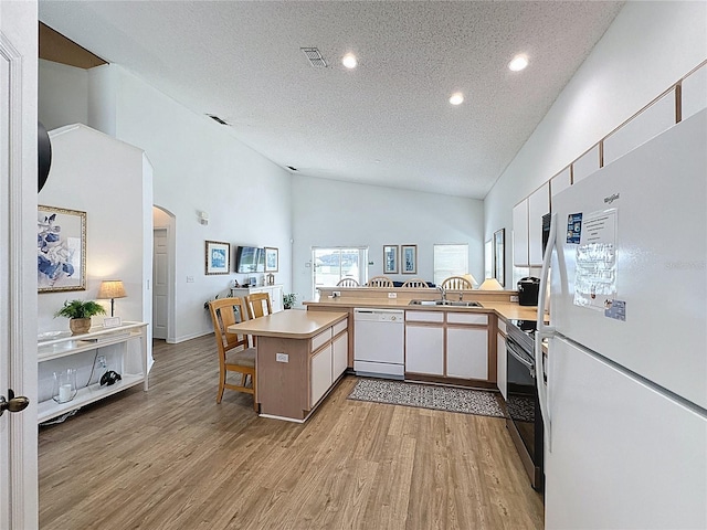 344 Bloomingdale Dr, Davenport, FL 33897 - kitchen with white appliances, a peninsula, a textured ceiling, light wood finished floors, and light countertops