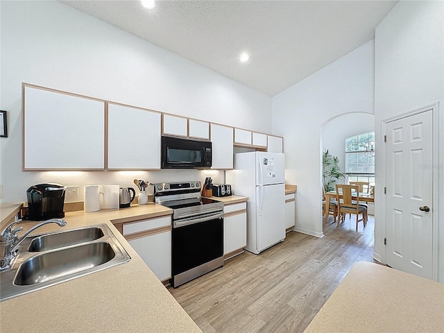344 Bloomingdale Dr, Davenport, FL 33897 - kitchen with stainless steel electric stove, black microwave, freestanding refrigerator, white cabinets, and high vaulted ceiling