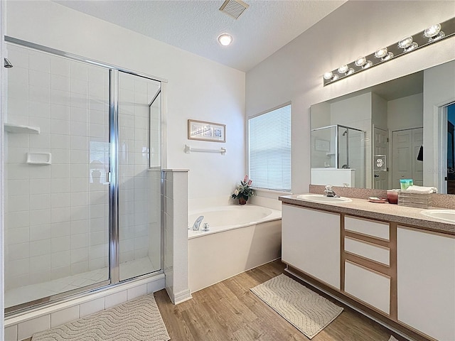 344 Bloomingdale Dr, Davenport, FL 33897 - bathroom featuring a stall shower, a garden tub, double vanity, wood finished floors, and a textured ceiling
