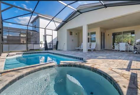 8937 Amelia Downs Trl, Kissimmee, FL 34747 - view of pool with a patio area, a pool with connected hot tub, outdoor dining area, and glass enclosure