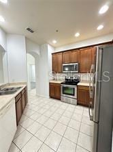 3351 Whitestone Cir Unit 204, Kissimmee, FL 34741 - kitchen with stainless steel appliances, arched walkways, light countertops, light tile patterned flooring, and recessed lighting