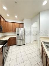 3351 Whitestone Cir Unit 204, Kissimmee, FL 34741 - kitchen with appliances with stainless steel finishes, light countertops, light tile patterned floors, recessed lighting, and brown cabinets