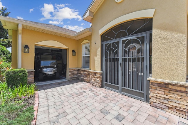 217 Sorrento Rd, Poinciana, FL 34759 - entrance to property featuring stucco siding, an attached garage, and stone siding