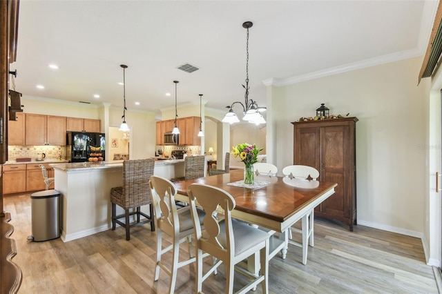 217 Sorrento Rd, Poinciana, FL 34759 - dining space with light wood-style flooring, ornamental molding, a chandelier, recessed lighting, and arched walkways