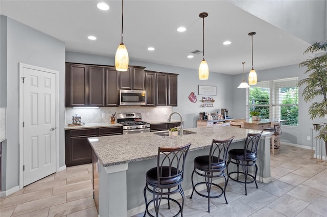 12353 Hammock Hill Dr, Clermont, FL 34711 - kitchen with appliances with stainless steel finishes, decorative backsplash, dark brown cabinetry, recessed lighting, and a kitchen island with sink