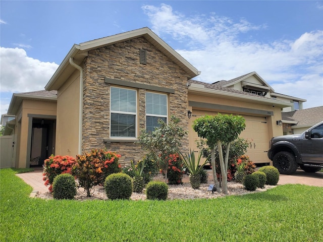 1456 Sourwood Dr, Ocoee, FL 34761 - view of side of home with stone siding, an attached garage, stucco siding, a yard, and driveway