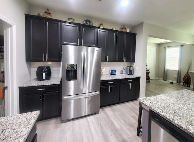 1456 Sourwood Dr, Ocoee, FL 34761 - kitchen featuring stainless steel appliances, dark cabinetry, backsplash, and light wood-type flooring