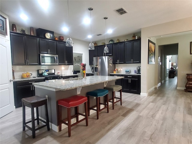 1456 Sourwood Dr, Ocoee, FL 34761 - kitchen featuring appliances with stainless steel finishes, decorative backsplash, a breakfast bar area, light wood-style flooring, and light stone counters