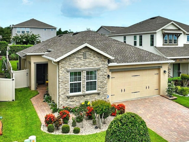 1456 Sourwood Dr, Ocoee, FL 34761 - view of front of house featuring stone siding, a garage, driveway, and roof with shingles