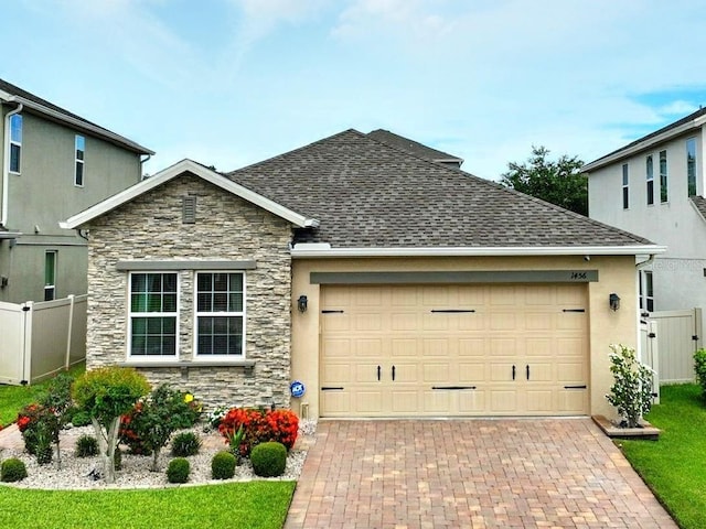 1456 Sourwood Dr, Ocoee, FL 34761 - view of front of house with stone siding, an attached garage, decorative driveway, a shingled roof, and stucco siding