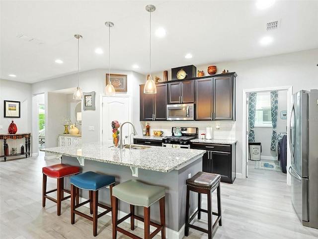 1456 Sourwood Dr, Ocoee, FL 34761 - kitchen with stainless steel appliances, light wood-style floors, a breakfast bar, light stone counters, and an island with sink