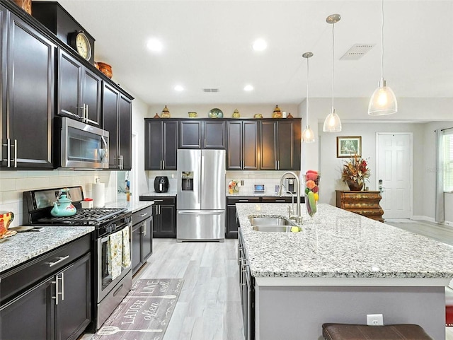 1456 Sourwood Dr, Ocoee, FL 34761 - kitchen featuring stainless steel appliances, light wood finished floors, backsplash, light stone countertops, and recessed lighting