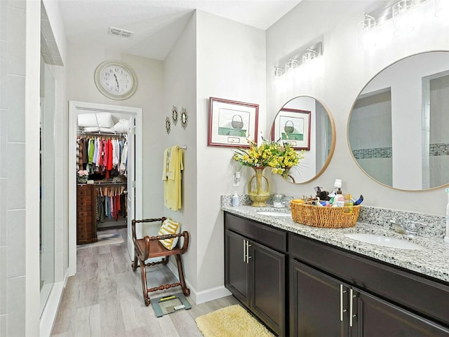 1456 Sourwood Dr, Ocoee, FL 34761 - bathroom with double vanity, wood finished floors, a spacious closet, and a stall shower