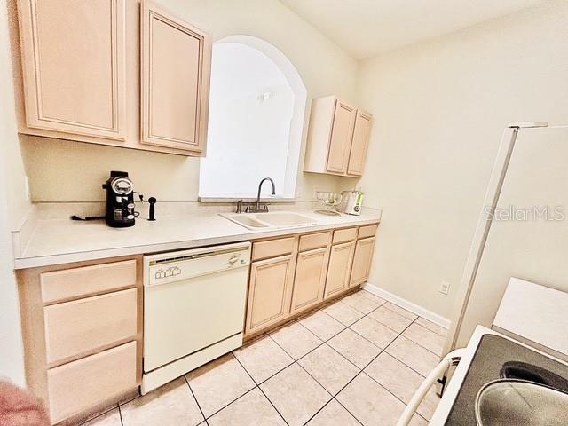13500 Turtle Marsh Loop Unit 17, Orlando, FL 32837 - kitchen featuring white dishwasher, cream cabinetry, light tile patterned floors, and light countertops