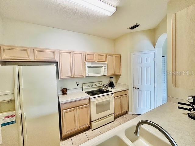 13500 Turtle Marsh Loop Unit 17, Orlando, FL 32837 - kitchen featuring white appliances, light brown cabinets, arched walkways, light countertops, and light tile patterned floors