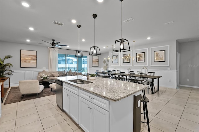 2131 Lelani Cir, Davenport, FL 33897 - kitchen with light tile patterned floors, stainless steel dishwasher, light stone counters, an island with sink, and white cabinetry