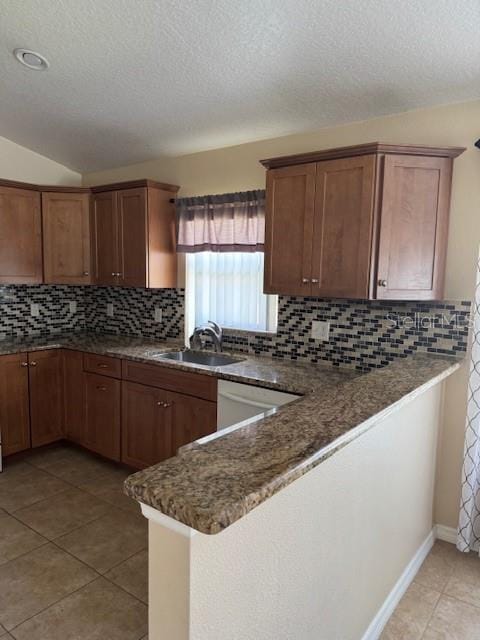 5435 Bryce Canyon Dr, Kissimmee, FL 34758 - kitchen featuring decorative backsplash, light tile patterned floors, a textured ceiling, a peninsula, and brown cabinetry
