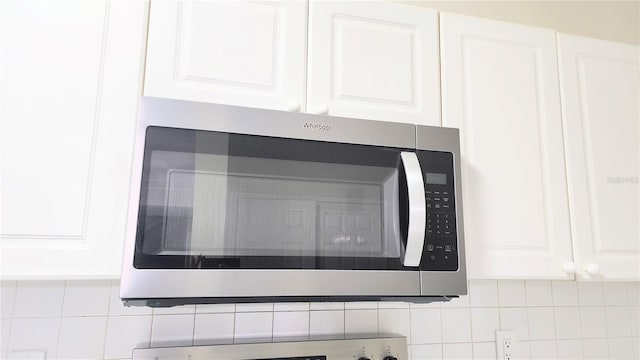 235 Goldenrain Dr Unit 102, Kissimmee, FL 34747 - kitchen view of stainless steel microwave, white cabinetry, and decorative backsplash
