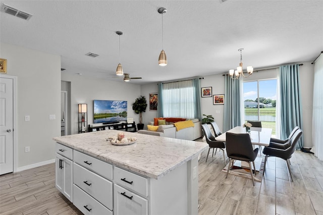 2436 Bulrush Dr, Saint Cloud, FL 34769 - kitchen featuring wood tiled floors, a kitchen island, a chandelier, pendant lighting, and white cabinets
