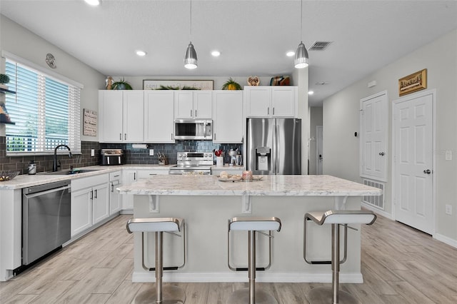 2436 Bulrush Dr, Saint Cloud, FL 34769 - kitchen with stainless steel appliances, a breakfast bar, light wood-style flooring, decorative backsplash, and recessed lighting