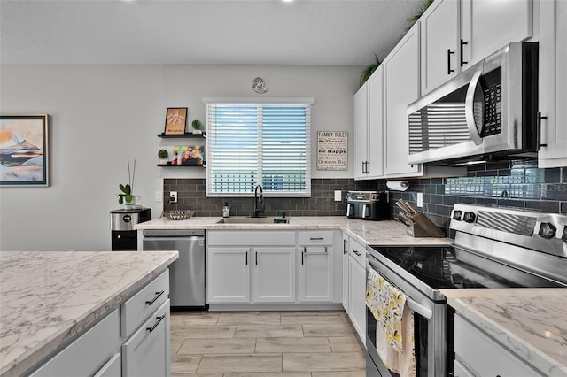 2436 Bulrush Dr, Saint Cloud, FL 34769 - kitchen with stainless steel appliances, decorative backsplash, white cabinets, and light stone counters