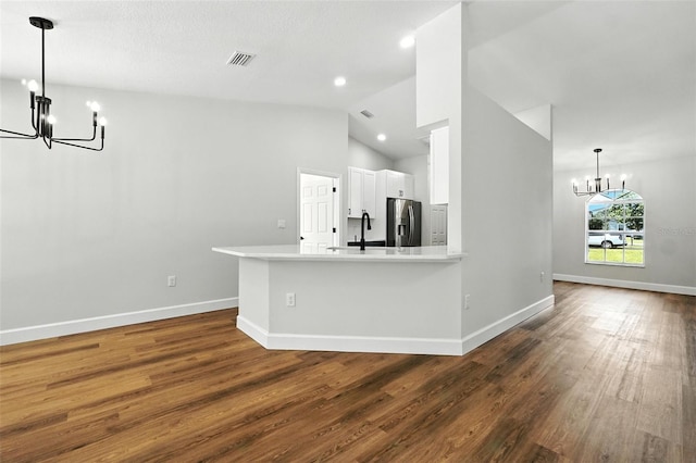 4635 Deer Run Rd, Saint Cloud, FL 34772 - kitchen with a chandelier, stainless steel fridge, wood finished floors, white cabinets, and high vaulted ceiling