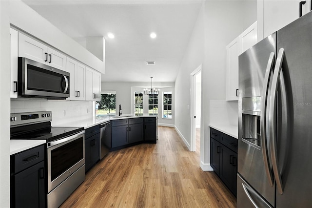 4635 Deer Run Rd, Saint Cloud, FL 34772 - kitchen with stainless steel appliances, light wood-style flooring, white cabinetry, a chandelier, and recessed lighting