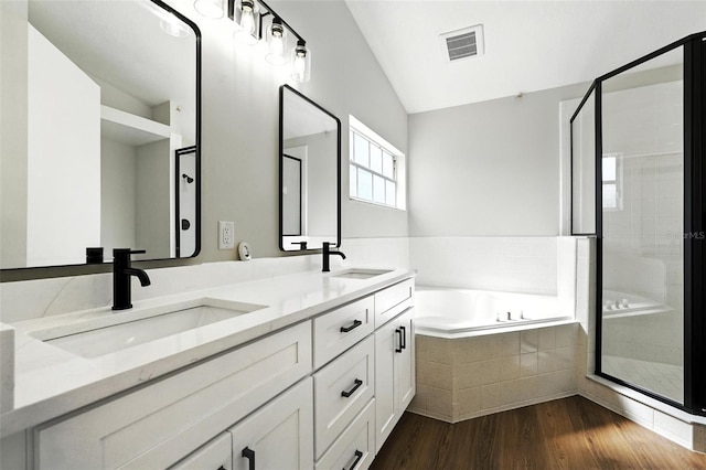 4635 Deer Run Rd, Saint Cloud, FL 34772 - full bath with vaulted ceiling, a bath, a stall shower, double vanity, and wood finished floors