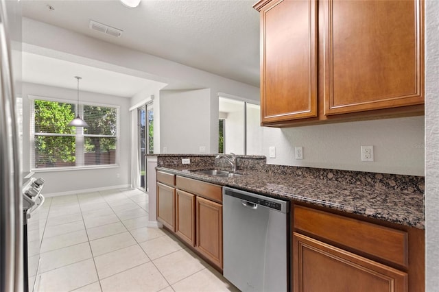 8309 Bella Vida Cir Unit 8309, Davenport, FL 33896 - kitchen featuring appliances with stainless steel finishes, dark stone counters, brown cabinets, light tile patterned floors, and pendant lighting