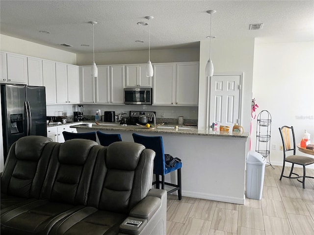 3799 Cedar Hammock Trl, Saint Cloud, FL 34772 - kitchen with appliances with stainless steel finishes, tasteful backsplash, a textured ceiling, and hanging light fixtures