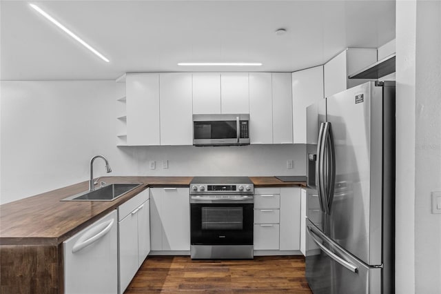 1645 Windsor Oak Ct, Kissimmee, FL 34744 - kitchen featuring stainless steel appliances, wooden counters, a peninsula, dark wood-type flooring, and white cabinetry