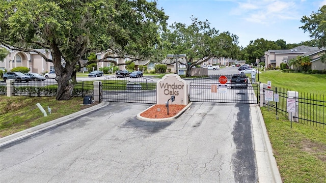 1645 Windsor Oak Ct, Kissimmee, FL 34744 - view of asphalt street featuring a residential view, a gate, a gated entry, and traffic signs