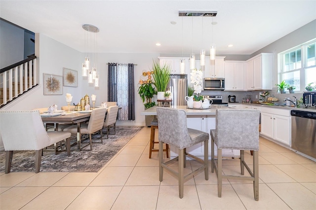 2463 Volunteer Ave, Kissimmee, FL 34744 - kitchen with stainless steel appliances, a kitchen island, a breakfast bar area, white cabinetry, and light tile patterned flooring