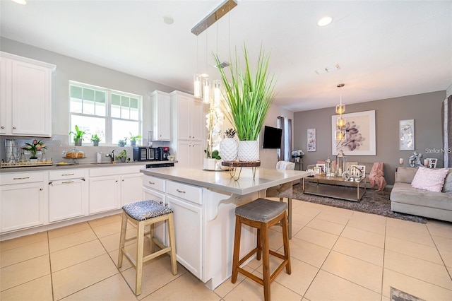2463 Volunteer Ave, Kissimmee, FL 34744 - kitchen with open floor plan, light tile patterned floors, a breakfast bar, white cabinetry, and tasteful backsplash