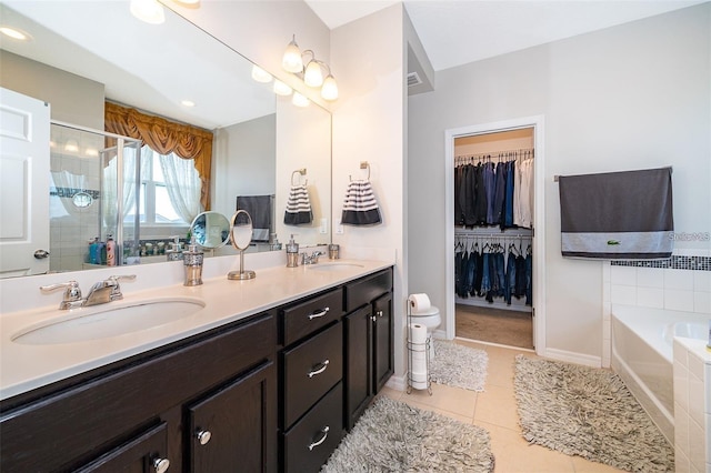 2463 Volunteer Ave, Kissimmee, FL 34744 - bathroom featuring double vanity, a bath, tile patterned floors, a tile shower, and a spacious closet
