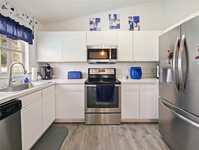 314 Clermont Dr, Kissimmee, FL 34759 - kitchen featuring appliances with stainless steel finishes, vaulted ceiling, light countertops, and white cabinets