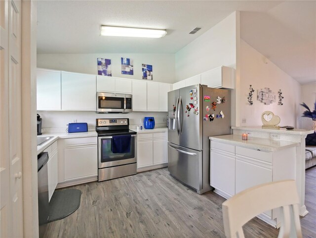314 Clermont Dr, Kissimmee, FL 34759 - kitchen featuring stainless steel appliances, light countertops, white cabinetry, light wood-style floors, and high vaulted ceiling