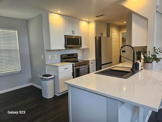 407 Darlington Loop, Davenport, FL 33896 - kitchen with appliances with stainless steel finishes, dark wood-style floors, a peninsula, white cabinetry, and recessed lighting