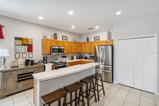 163 Tigerlily Ct, Davenport, FL 33837 - kitchen featuring stainless steel appliances, light tile patterned floors, a breakfast bar, recessed lighting, and a kitchen island with sink