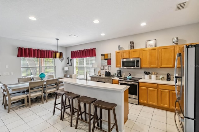 163 Tigerlily Ct, Davenport, FL 33837 - kitchen with stainless steel appliances, light countertops, recessed lighting, light tile patterned flooring, and a kitchen breakfast bar