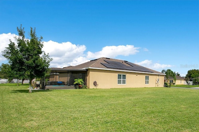3430 Harlequin Dr, Saint Cloud, FL 34772 - back of house featuring solar panels, a lawn, stucco siding, and a sunroom