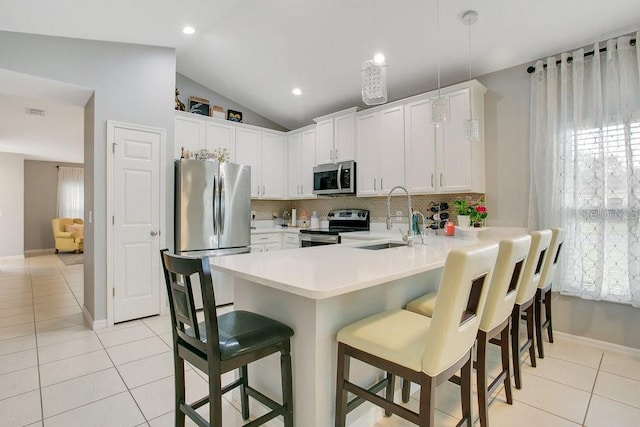 3430 Harlequin Dr, Saint Cloud, FL 34772 - kitchen with stainless steel appliances, light tile patterned flooring, a peninsula, lofted ceiling, and decorative backsplash