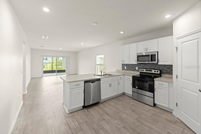 588 Meadow Bend Dr, Davenport, FL 33837 - kitchen featuring appliances with stainless steel finishes, a peninsula, light countertops, white cabinetry, and recessed lighting