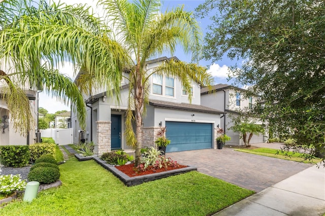 9878 Aurea Moss Ln, Orlando, FL 32832 - view of front of home with stucco siding, a garage, decorative driveway, a gate, and stone siding