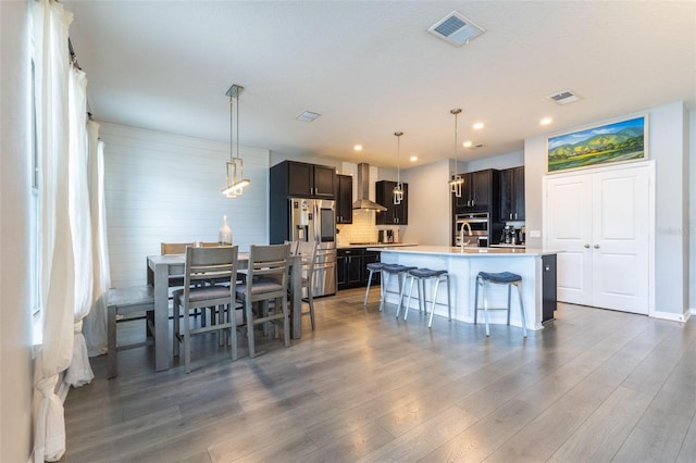 9878 Aurea Moss Ln, Orlando, FL 32832 - kitchen with stainless steel appliances, wood finished floors, light countertops, wall chimney exhaust hood, and recessed lighting
