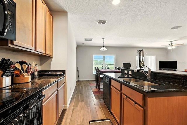 301 Sierra Way, Davenport, FL 33837 - kitchen with black appliances, light wood finished floors, dark stone countertops, a ceiling fan, and open floor plan