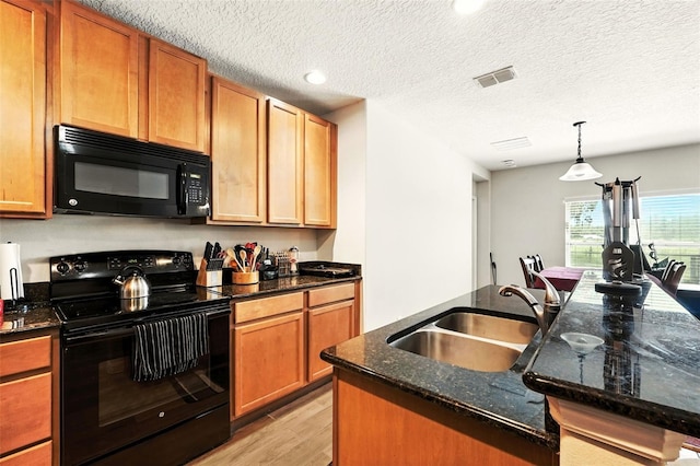 301 Sierra Way, Davenport, FL 33837 - kitchen featuring black appliances, light wood-style flooring, dark stone countertops, a kitchen island with sink, and recessed lighting