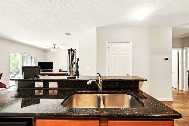 301 Sierra Way, Davenport, FL 33837 - kitchen featuring a textured ceiling, wood finished floors, dark stone countertops, open floor plan, and ceiling fan