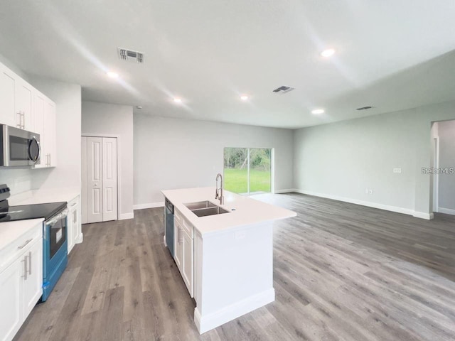 35 Pecan Run Crse, Ocala, FL 34472 - kitchen with stainless steel appliances, white cabinets, a center island with sink, wood finished floors, and light countertops